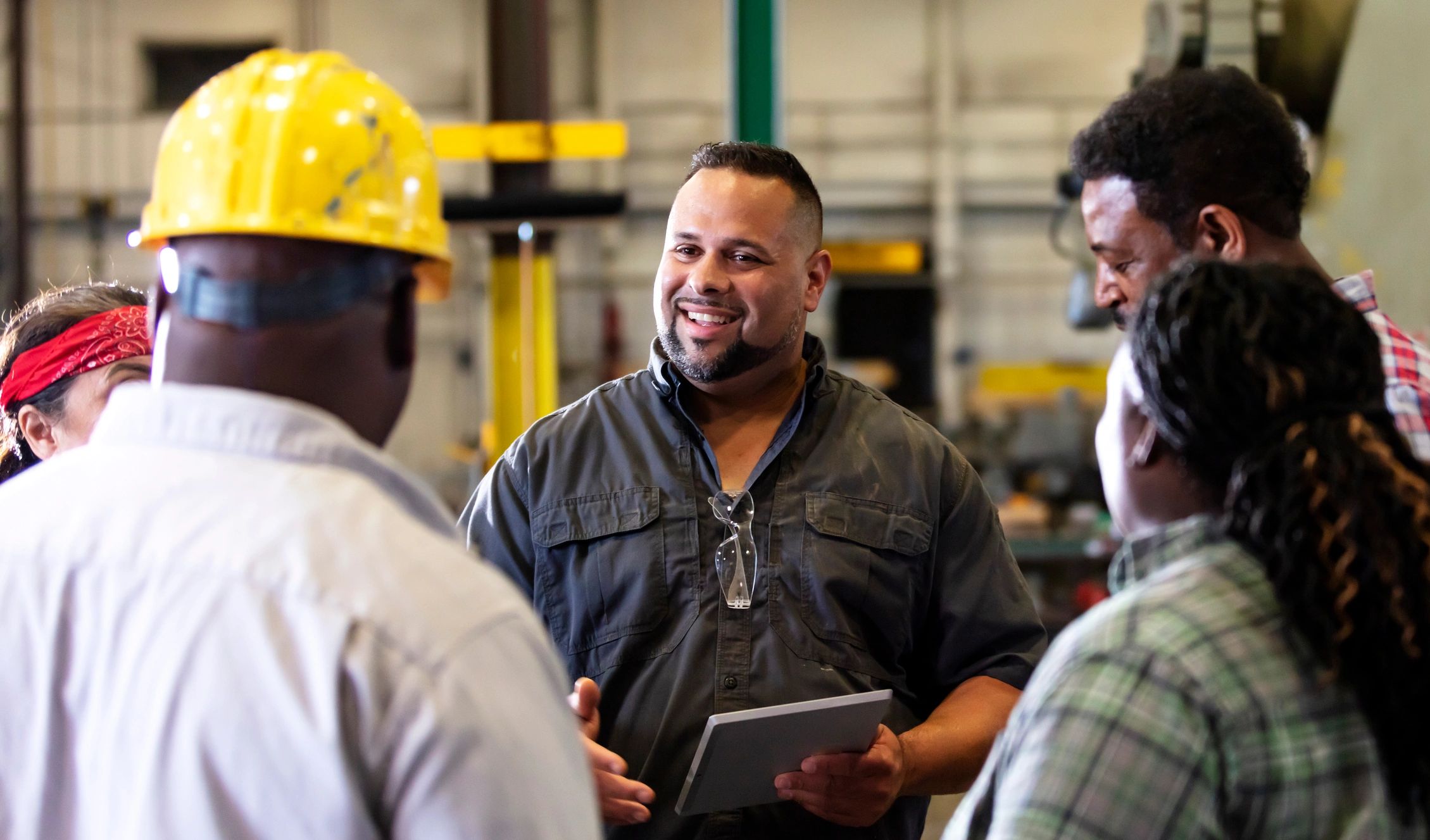 Factory team meeting around a tablet on the shop floor